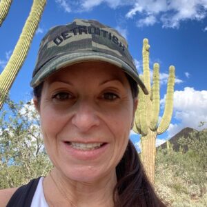 Allyson in ball cap outdoors with cactus