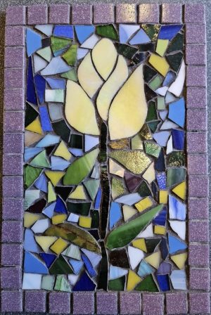 Glass tile mosaic with blue yellow and green background and a yellow tulip